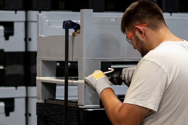 An oversized plastic container being hot-air welded in a factory.